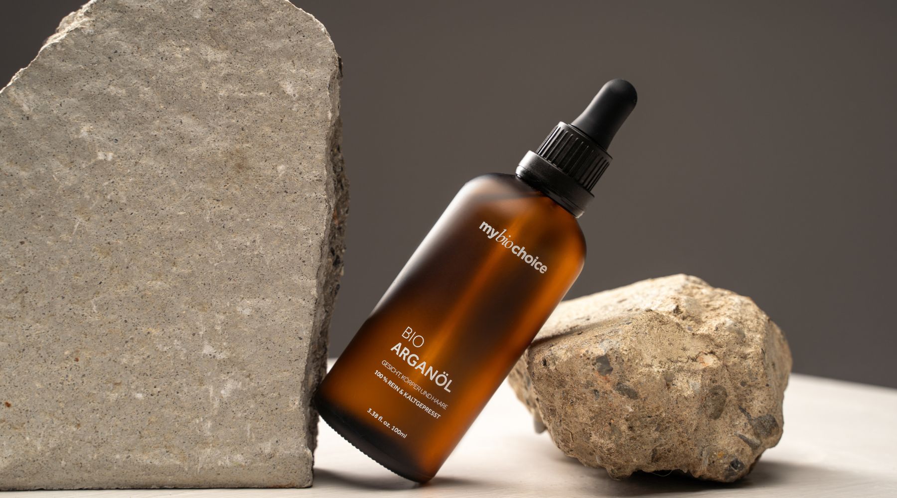 Bio Arganöl Flasche von mybiochoice zwischen Natursteinen – minimalistisches Produktfoto mit hochwertigem Pflegeöl.