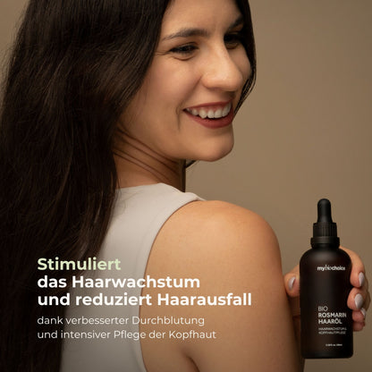 Lächelnde Frau mit gesundem, glänzendem Haar hält das Bio Rosmarin Haaröl von mybiochoice. Die Botschaft: „Stimuliert das Haarwachstum und reduziert Haarausfall“ – dank verbesserter Durchblutung und intensiver Pflege der Kopfhaut.